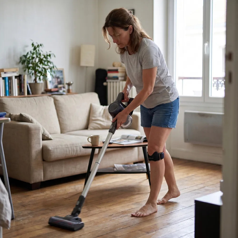 Femme qui passe l'aspirateur avec la sangle rotulienne